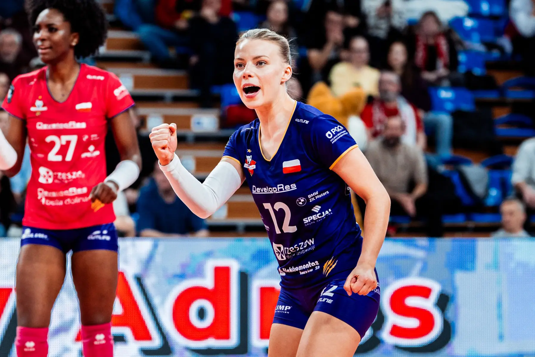 Aleksandra Szczygłowska in a purple and blue volleyball jersey celebrating on the court