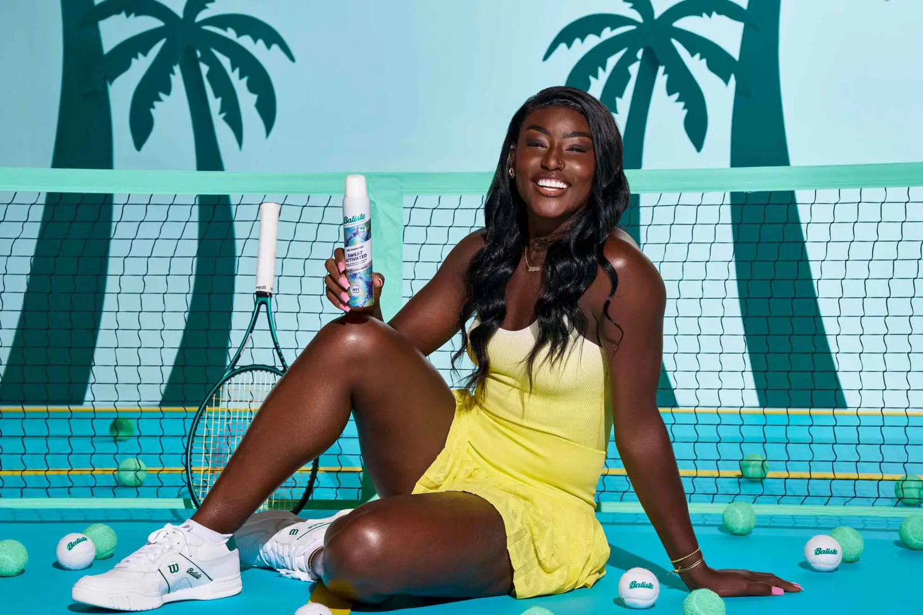 Tennis player Alycia Parks in a yellow dress sitting on a blue court holding a deodorant spray.