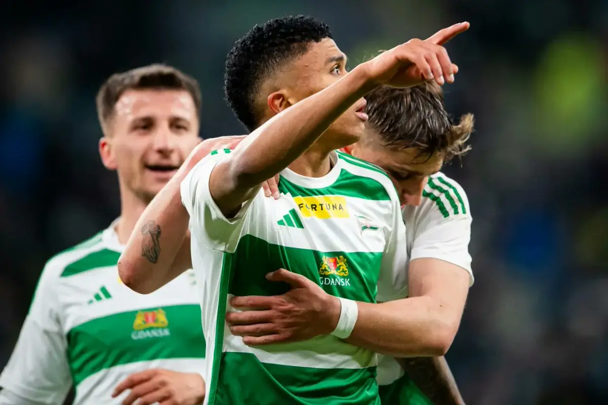Camilo Mena in a Lechia Gdańsk white and green striped jersey celebrating with teammates