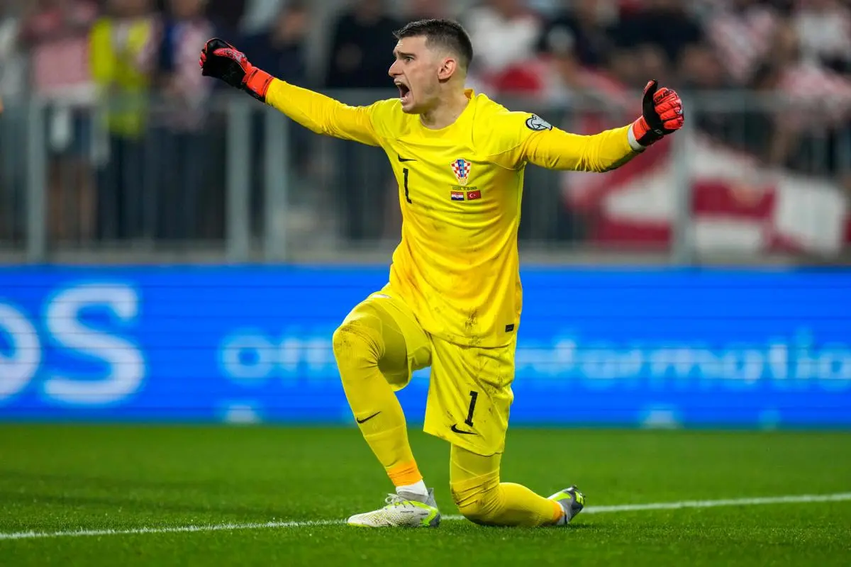 Dominik Livaković in a yellow Croatia goalkeeper kit celebrating on the pitch during a match