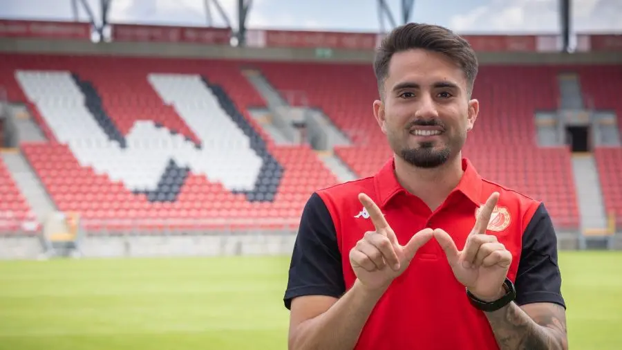 Fran Alvarez wearing a red and black Widzew Łódź polo shirt, posing in front of the stadium seats