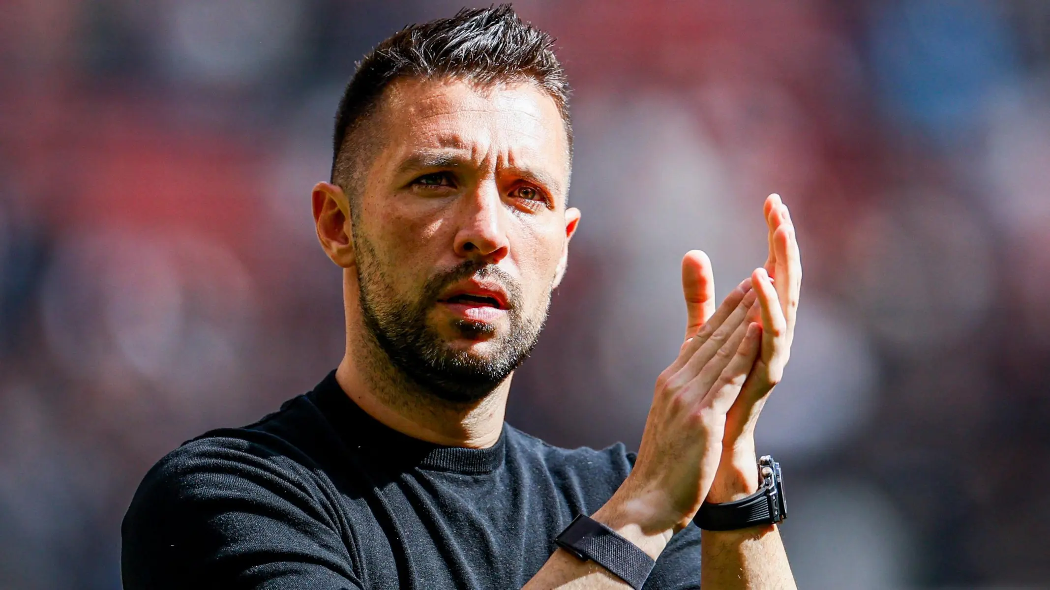 Francesco Farioli wearing a black t-shirt and clapping during a football match