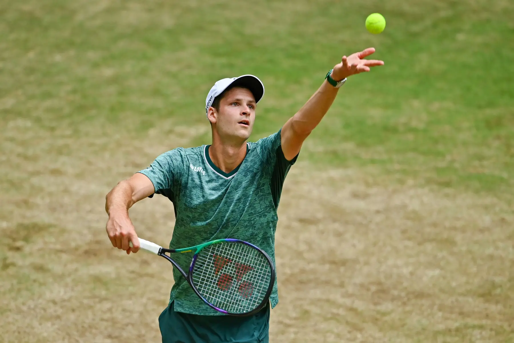 Hubert Hurkacz tossing a tennis ball into the air during a serve