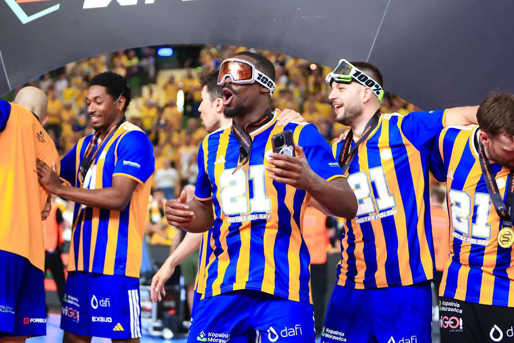 Industria Kielce handball players celebrating in blue and yellow striped jerseys