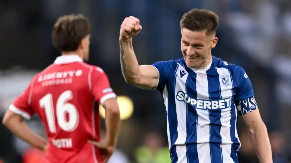Lech Poznań player in blue and white stripes celebrating next to an FC Thun player in red