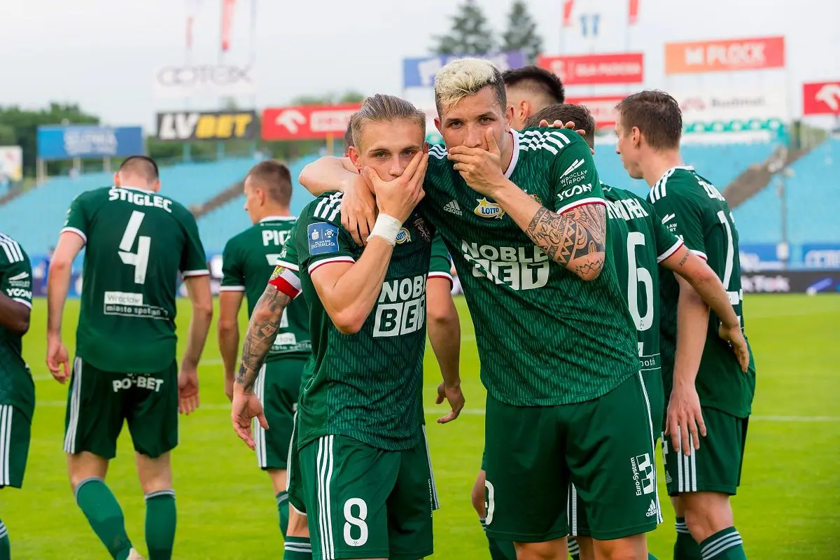 Śląsk Wrocław football players in green kits celebrating on the pitch during an Ekstraklasa match