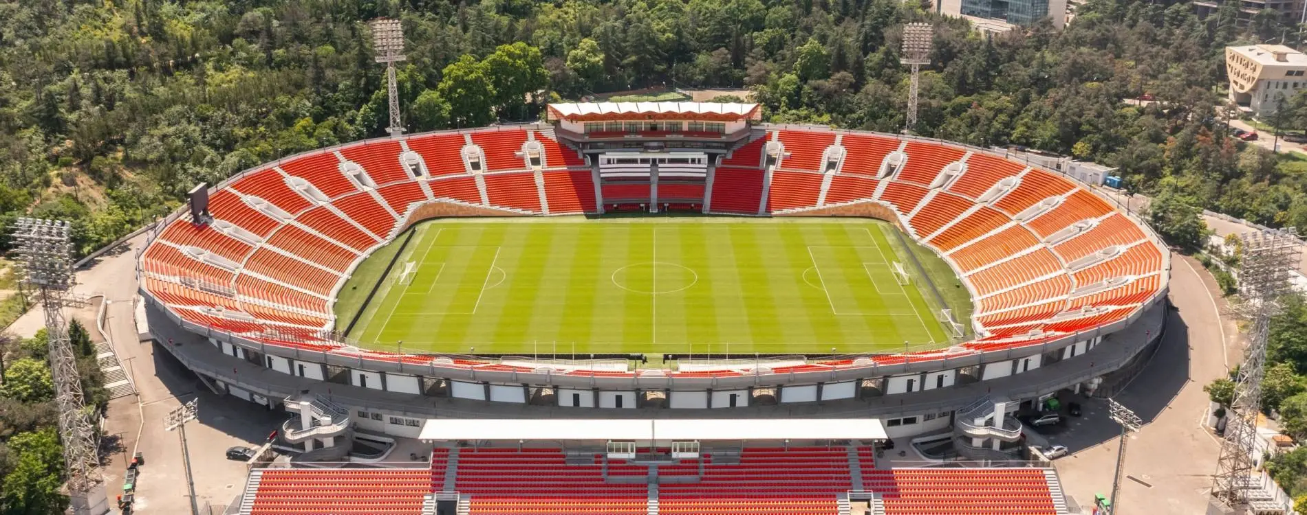 Aerial view of Mikheil Meskhi Stadium in Tbilisi with red seating and a green grass pitch