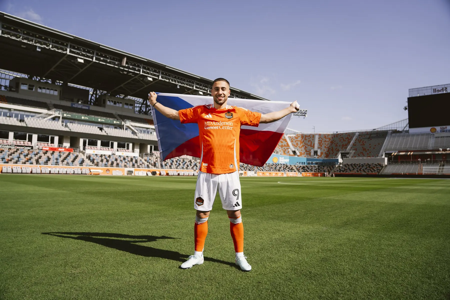 Ondrej Lingr in a Houston Dynamo kit holding the Czech Republic flag on a soccer field