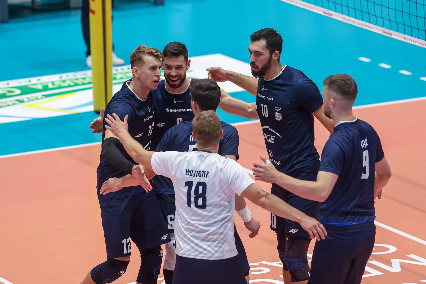 PGE Projekt Warszawa volleyball players celebrating on court, including player Wojtiszcze with number 18