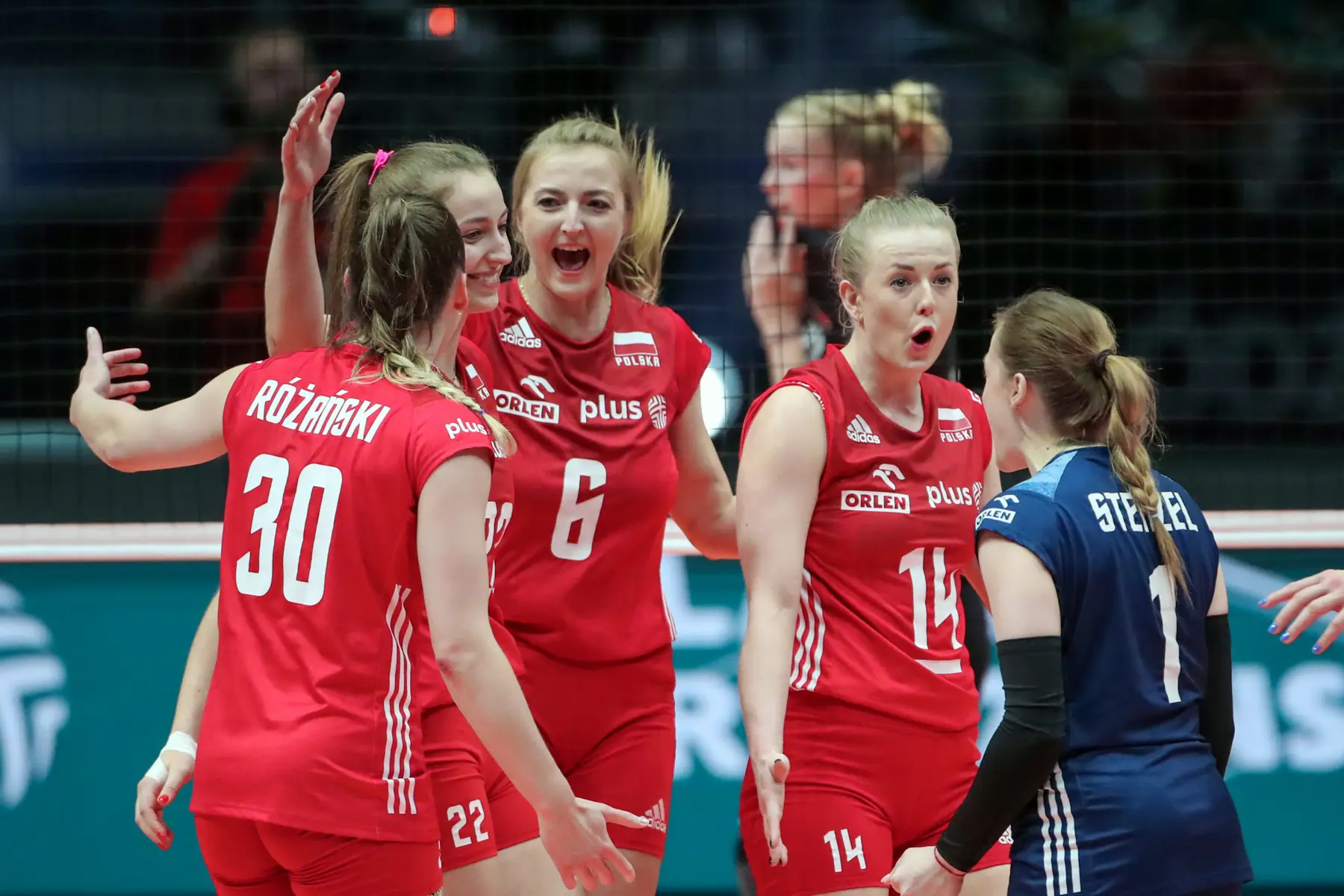 Polish women's national volleyball team in red jerseys celebrating on court during a match