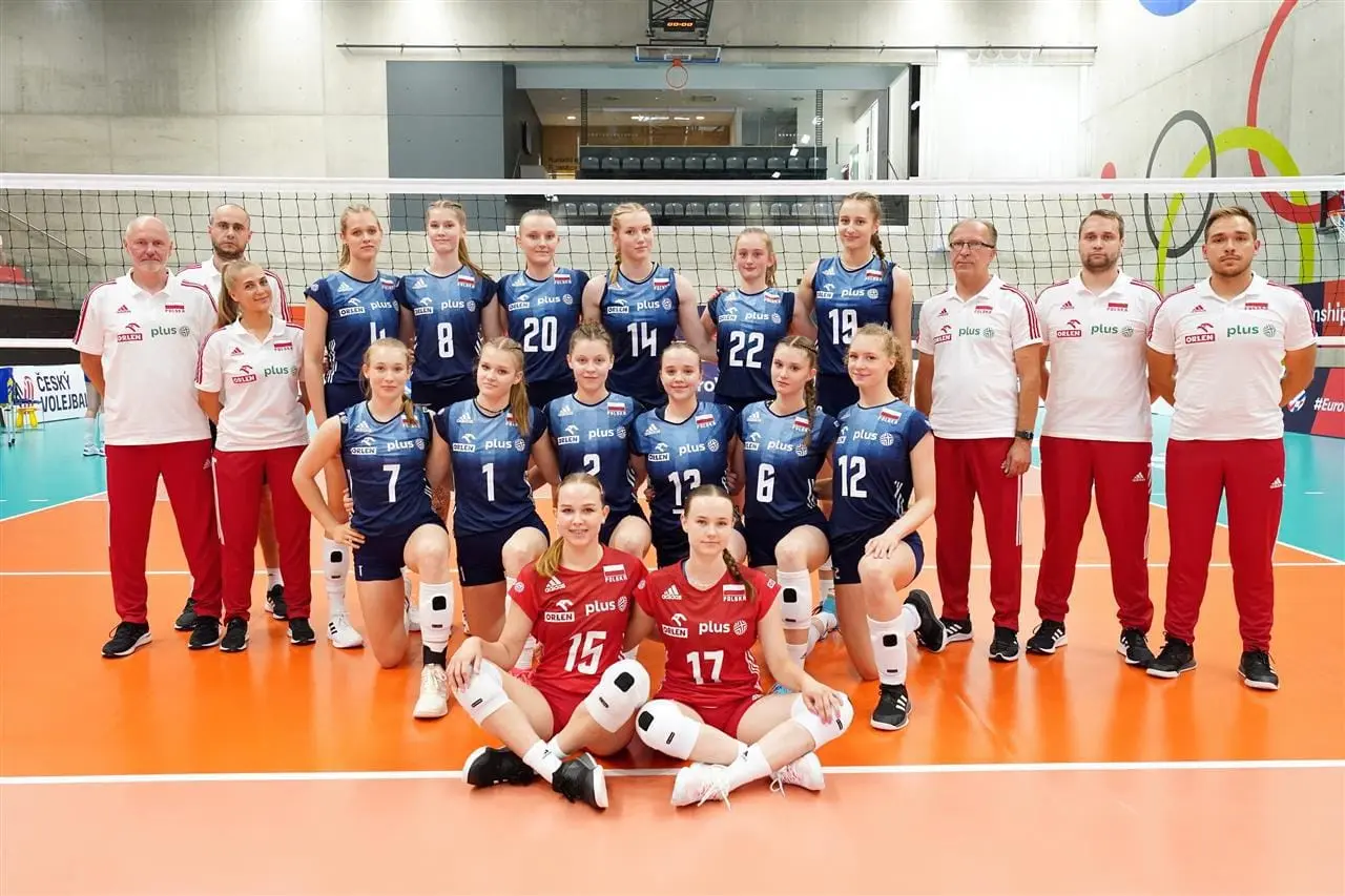 The Polish women's national youth volleyball team posing for a group photo on an indoor court.