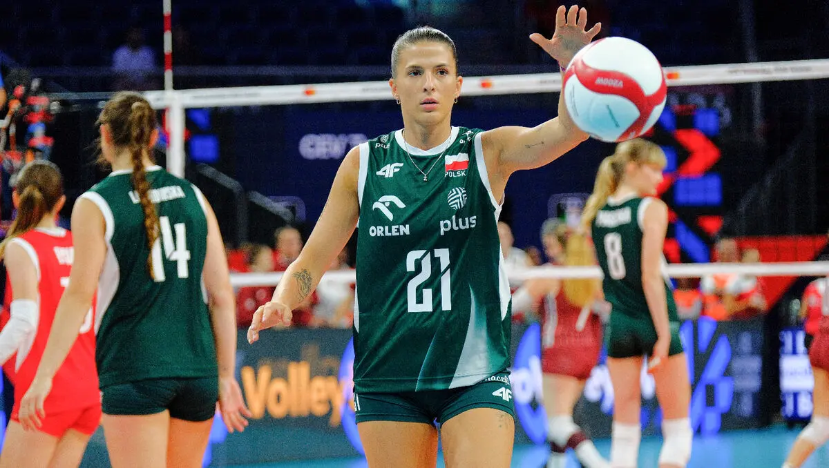 Polish women's national volleyball team player in a green jersey with number 21 preparing to hit the ball