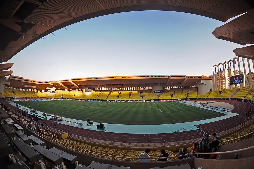 Wide-angle view of the empty pitch and yellow stands at Stade Louis II in Monaco