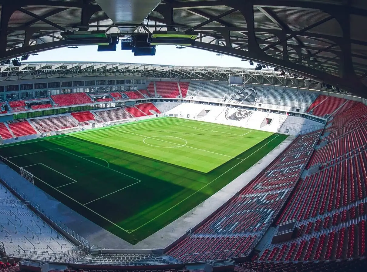 Wide angle view of Stadion Rakowa in Częstochowa with red seats and team logo on the pitch