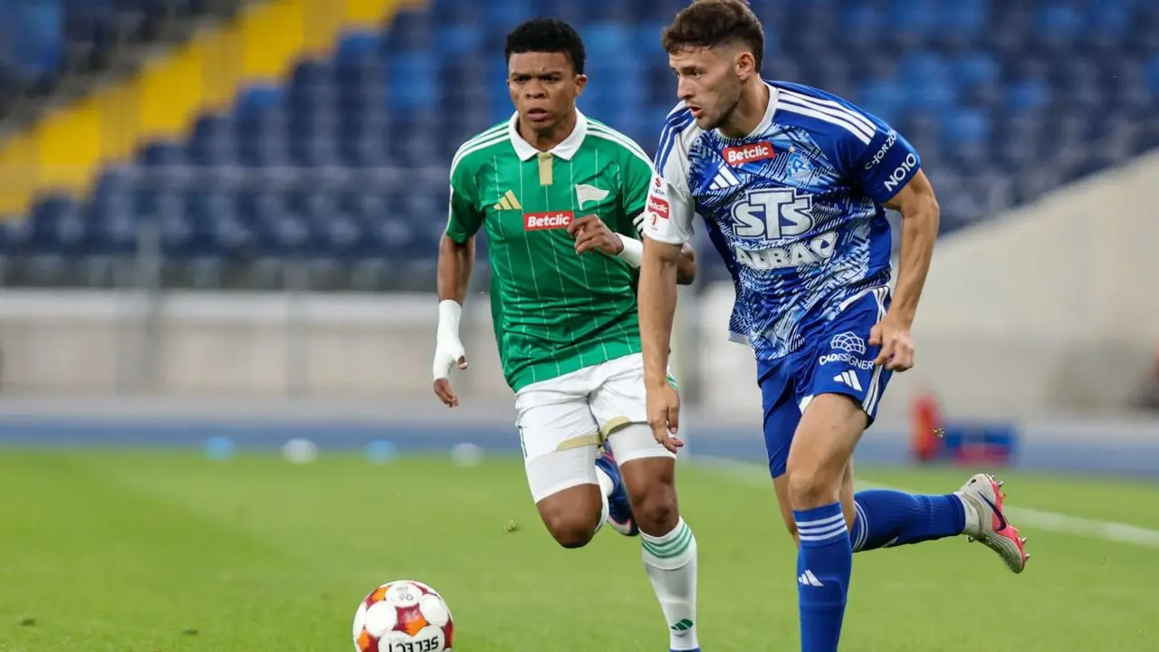Two football players, one in a green Stal Rzeszów kit and one in a blue Ruch Chorzów kit, competing for the ball.