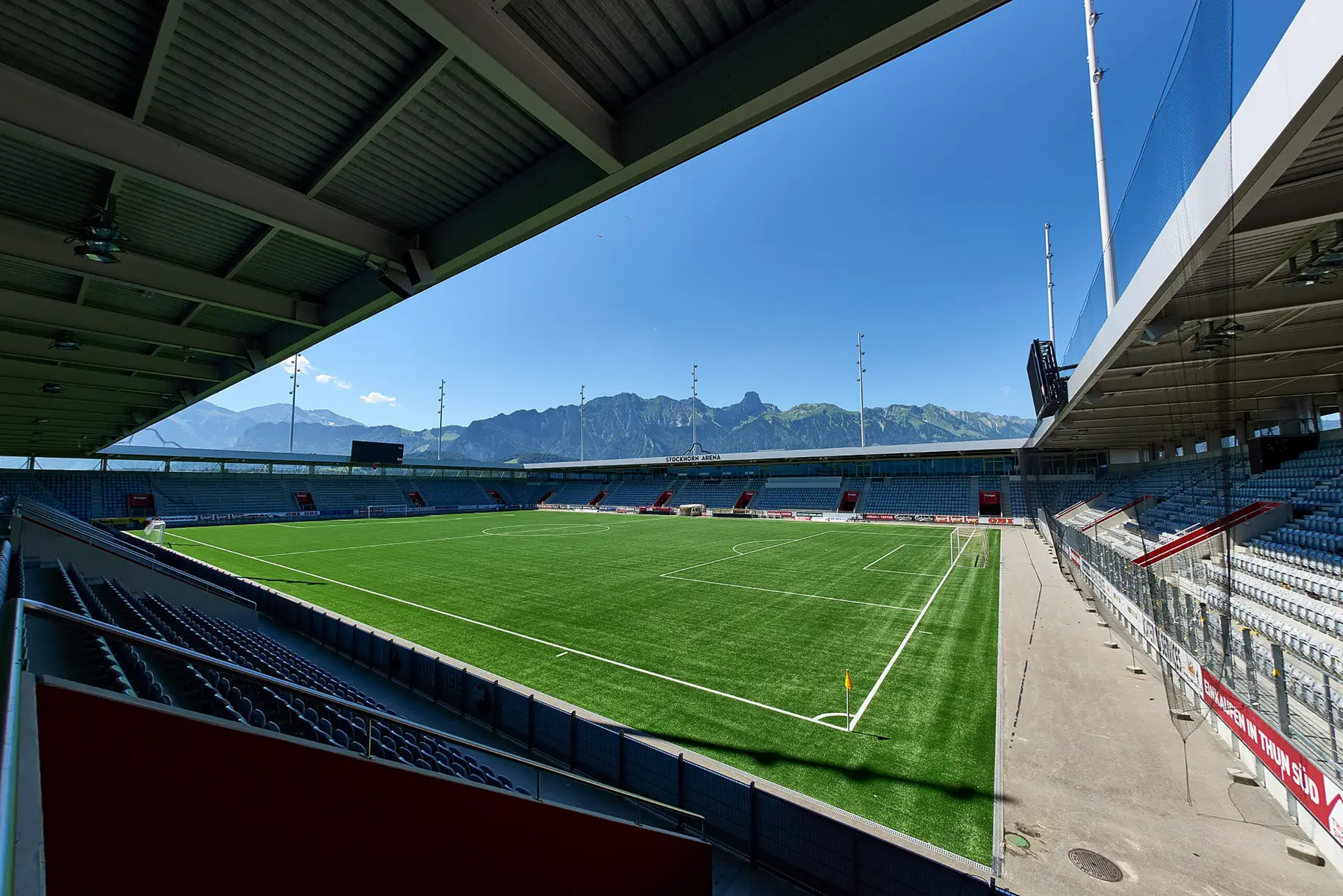 Wide view of Stockhorn Arena stadium in Thun with a green football pitch and mountains in the background