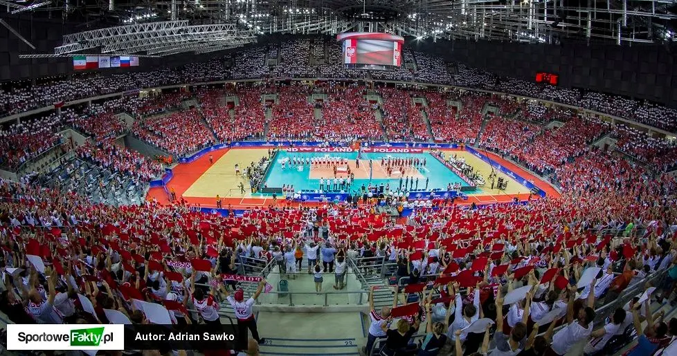 Wide shot of a volleyball match in Tauron Arena Krakow with fans waving red and white Polish flags.