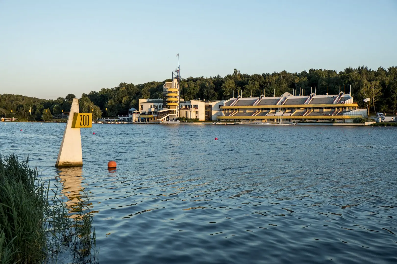 Wide shot of the rowing and canoeing course at Lake Malta in Poznan with yellow grandstands and a judge tower