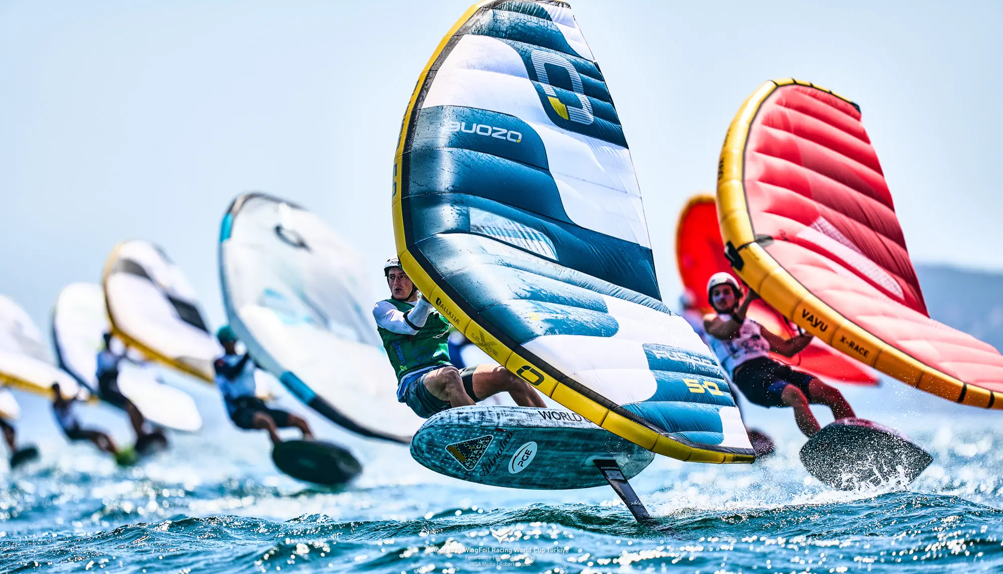 Wingfoilers racing on the water with colorful wings and hydrofoils during a competition