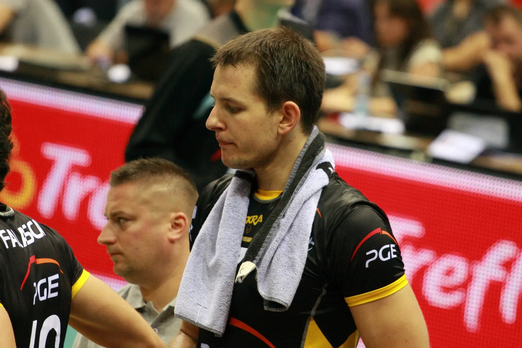 Bartosz Kurek w czarnej koszulce siatkarskiej z ręcznikiem na szyi.