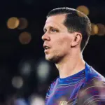 Portret Wojciecha Szczęsnego w stroju sportowym na tle rozmytego stadionu.