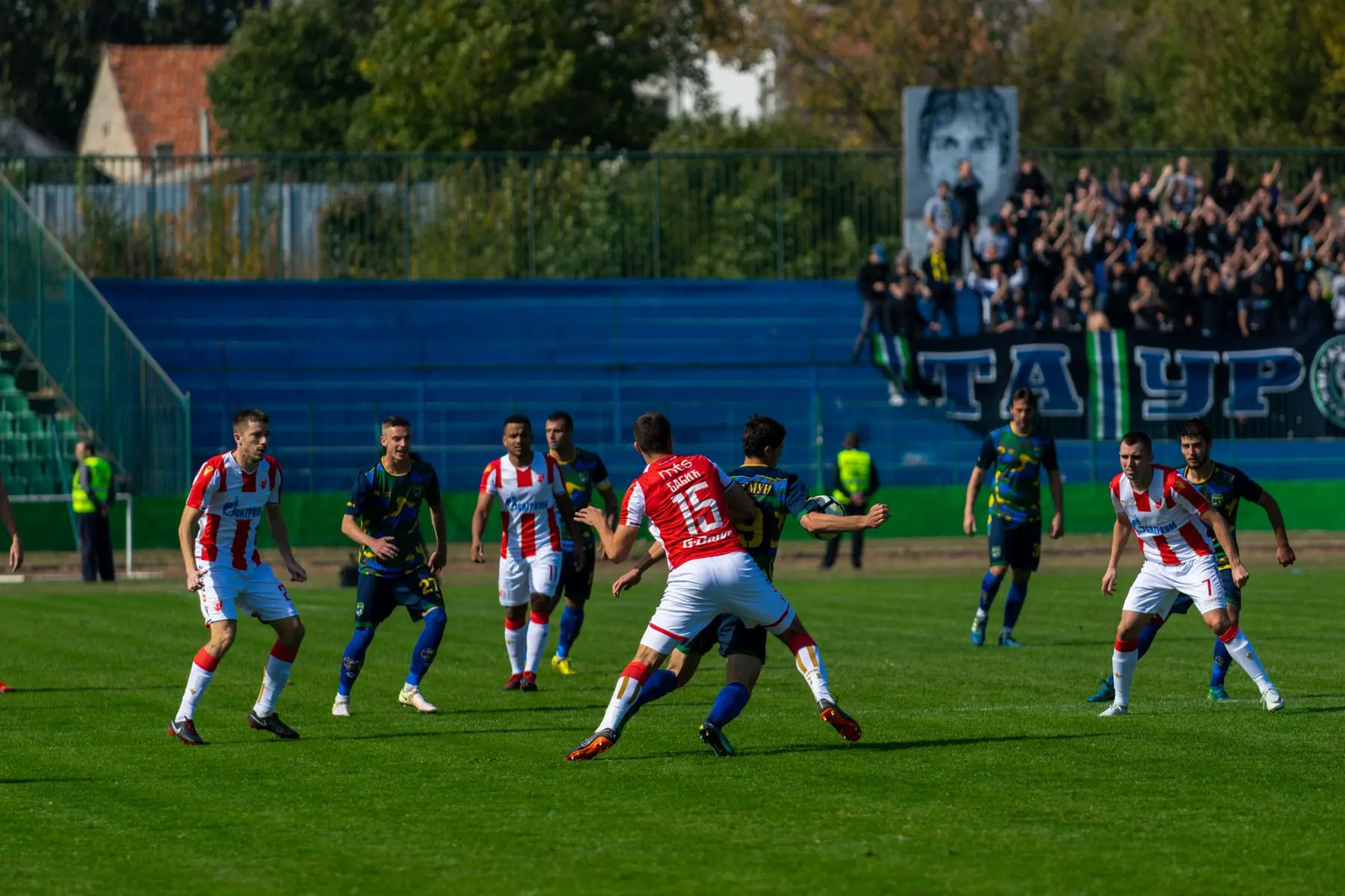 GKS Katowice football players in red and white striped jerseys during a match on a grass field