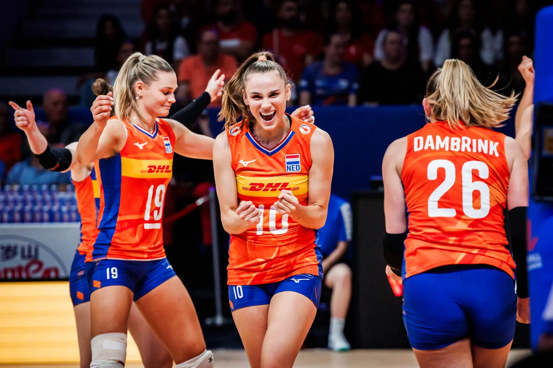 Netherlands women's national volleyball team players celebrating in orange uniforms during a match.