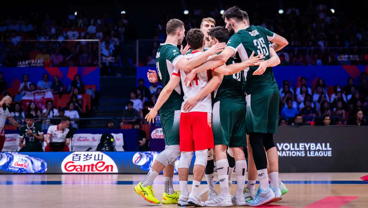 Polish national volleyball team players in green and white jerseys huddling on the court during a match