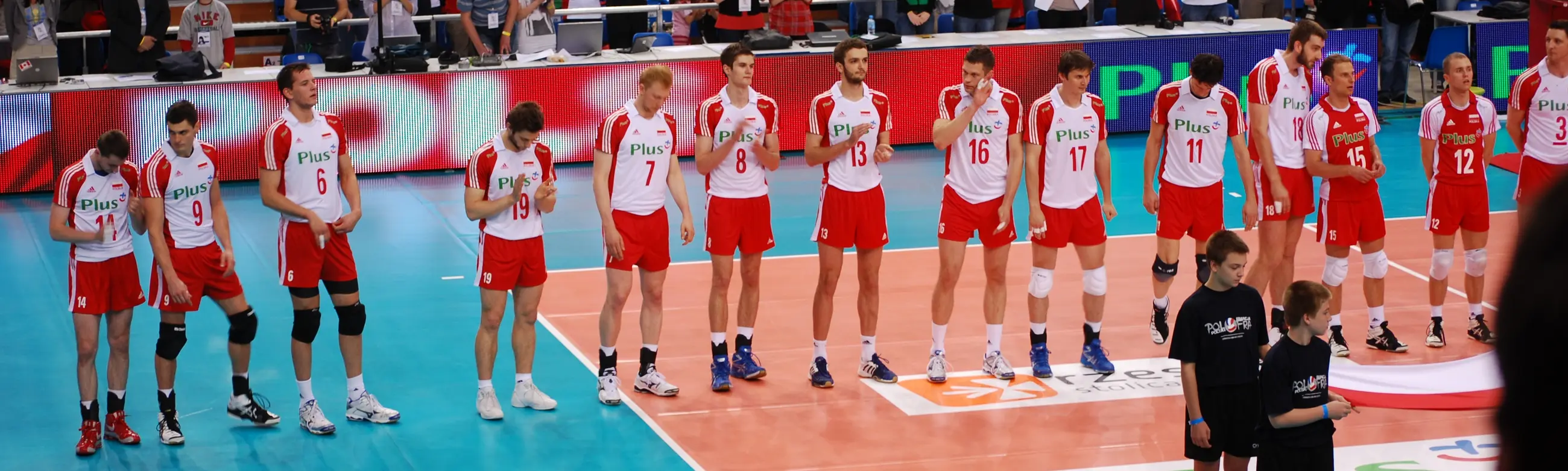 Zawodnicy reprezentacji Polski w piłce siatkowej mężczyzn w białoczerwonych strojach na boisku.